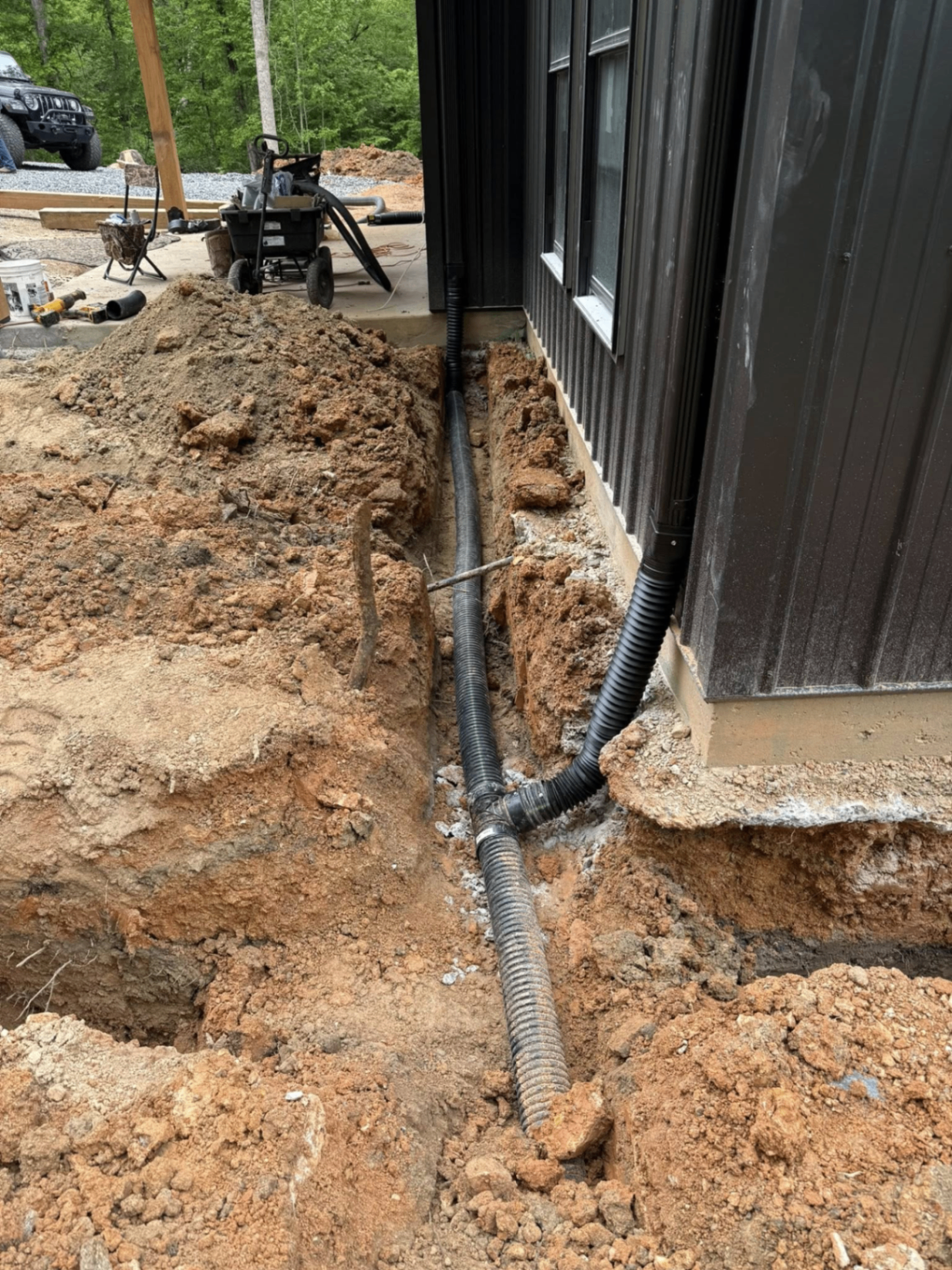 Drainage trench and downspout tie-in along new home foundation