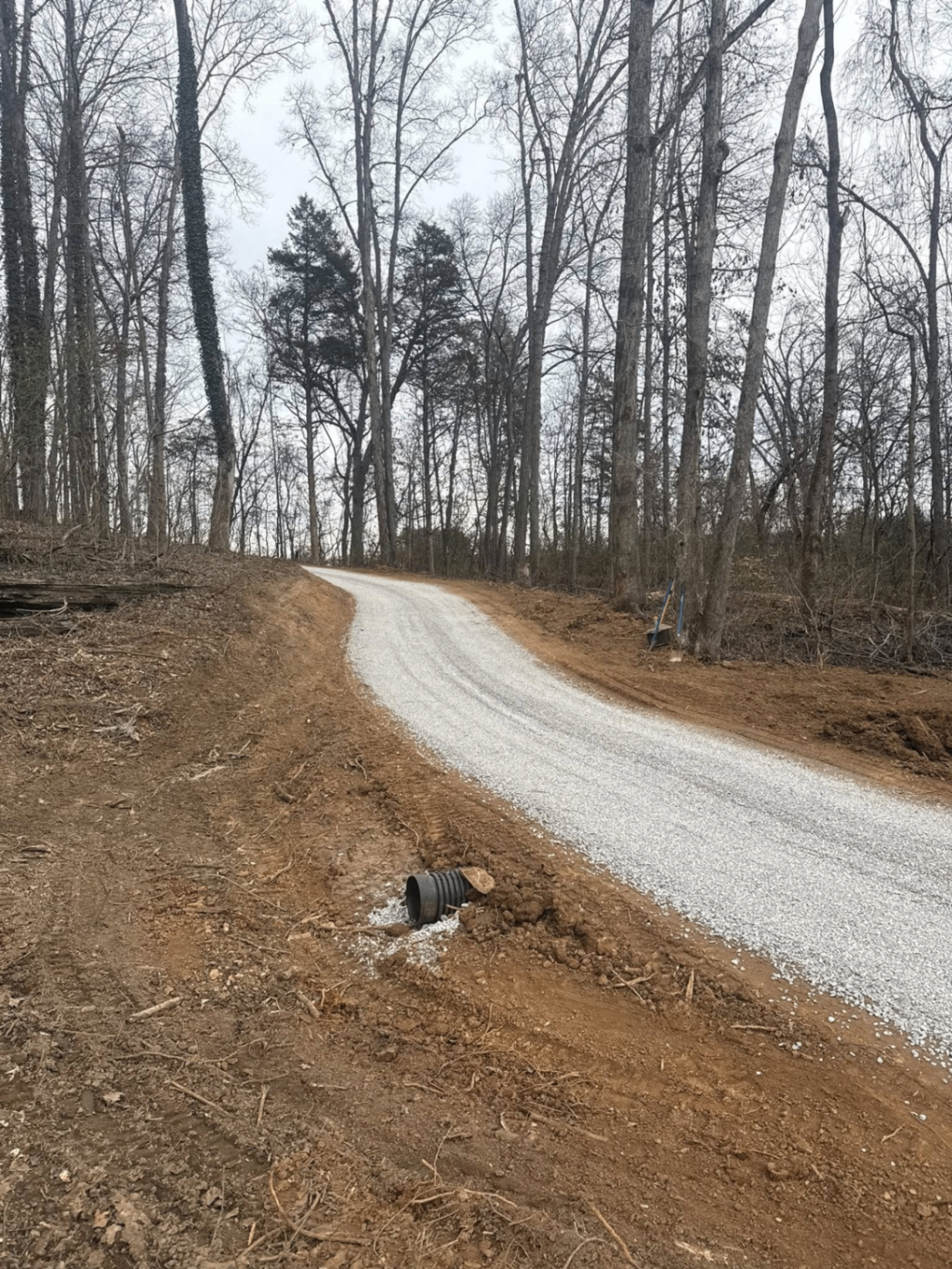 New gravel driveway through the woods with culvert pipe installed for drainage